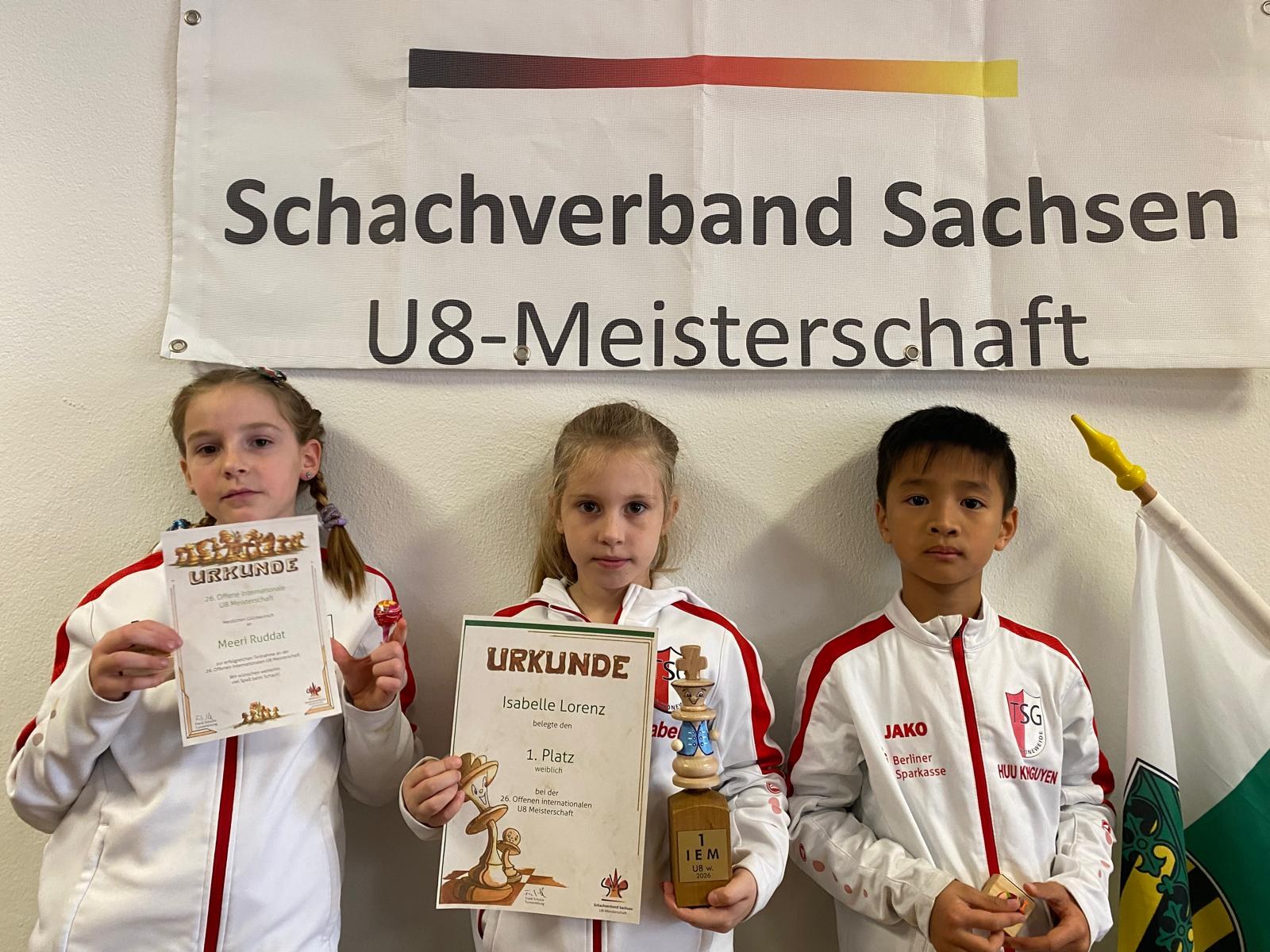 Isabelle Lorenz mit Pokal und Urkunde bei der Siegerehrung der U8-Meisterschaft in Sebnitz, daneben zwei TSG-Kinder